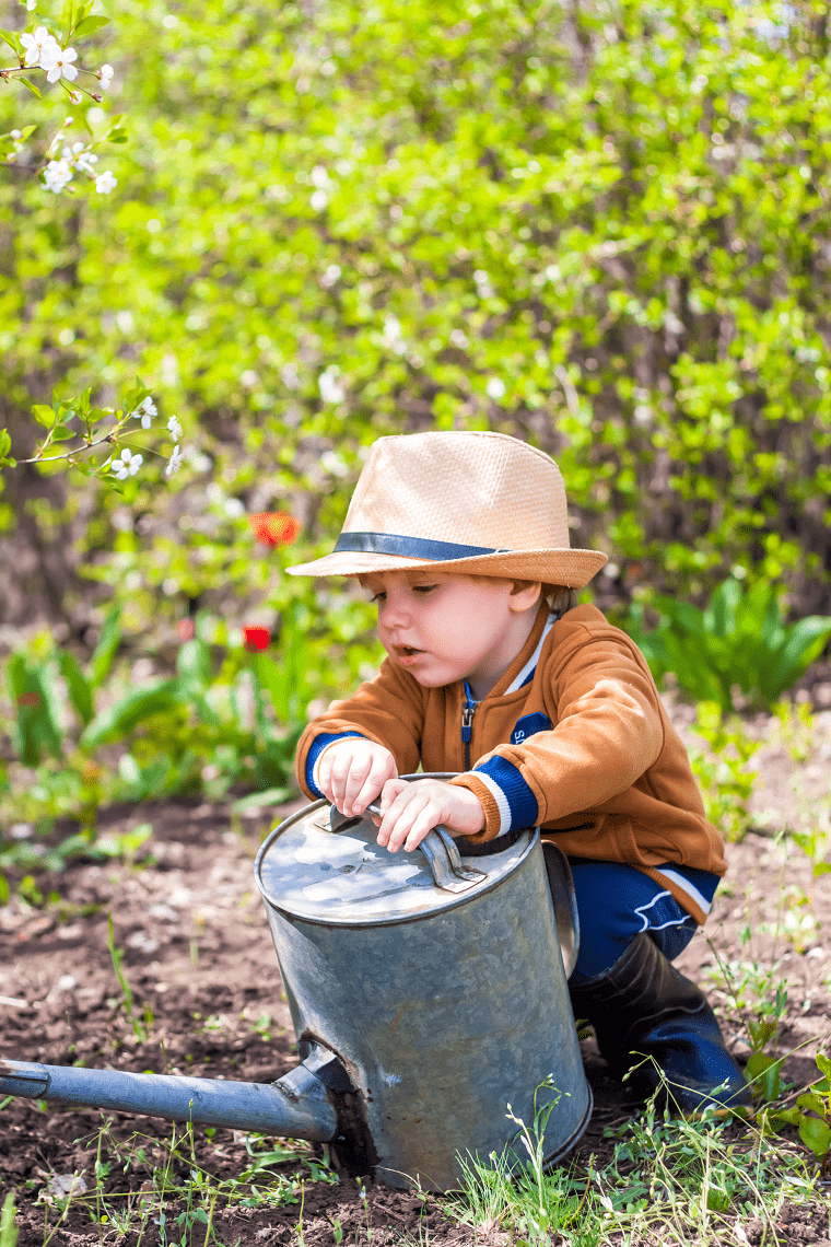 sensory-activities-for-toddlers-toddler-boy-wearing-a-hat-while-watering-plants-outdoors
