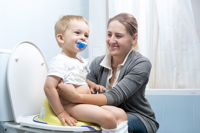 toilet training - mother holding son on toilet seat
