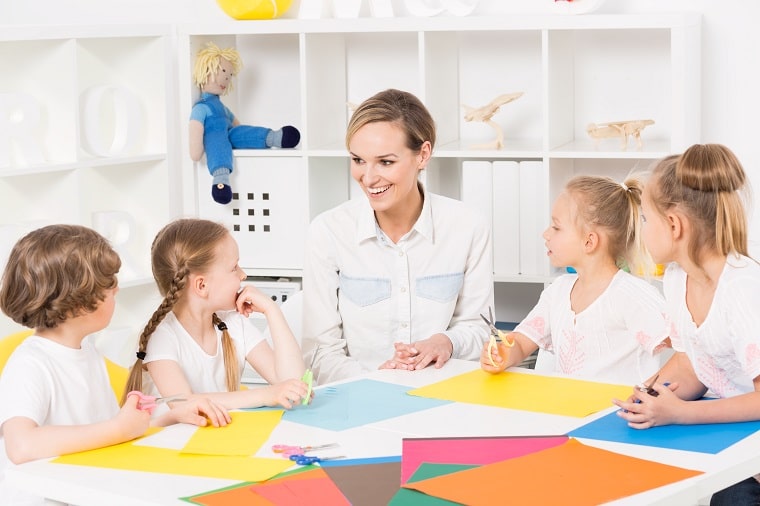 School Readiness Activities For Preschoolers - teacher and children doing a paper activity