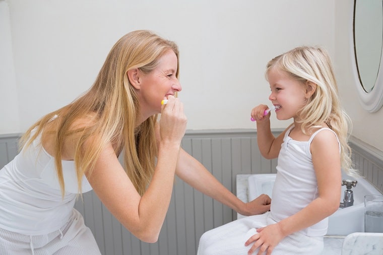how do routines help a child's development - mother and child brushing teeth together