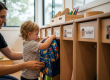 Child placing backpack in organized cubby during morning routine at Sunshine Coast early learning centre