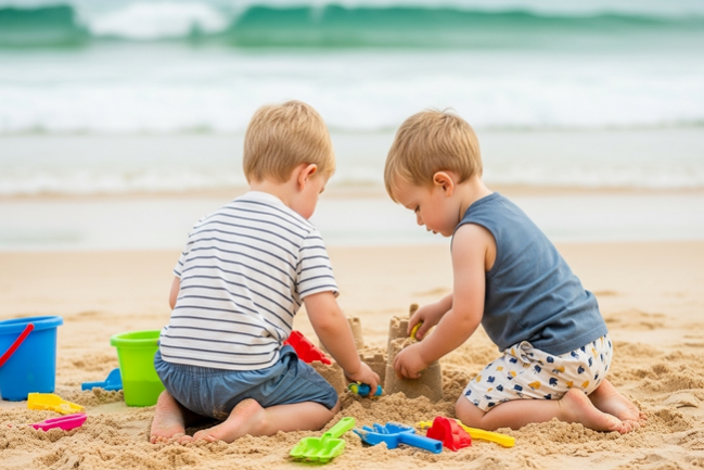 Two toddlers collaboratively building a sandcastle at a Sunshine Coast beach, demonstrating social skill development through natural play